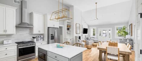 Cocina moderna con armarios blancos, electrodomésticos de acero inoxidable y una isla central.