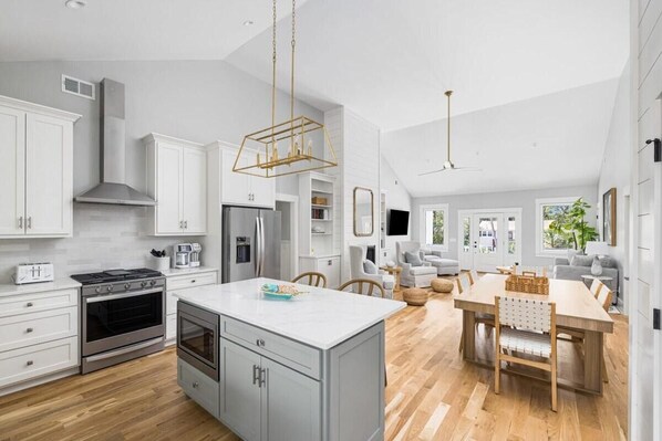 A modern kitchen with white cabinetry, stainless steel appliances, and a central island.