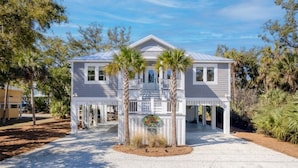 A two-story house with a covered porch, palm trees, and a sign in front. - Jungle House-Heated Pool-Pet Friendly-Luxury (Edisto Island)