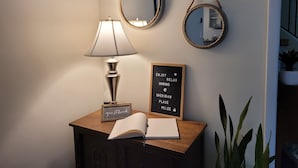 Een houten bureau met een lamp, een gastenboek en een lijst met een tekst.