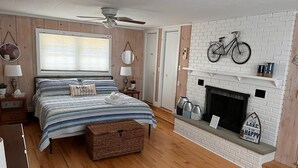 Een slaapkamer met een bed, een open haard, een fiets en een raam met zonwering.