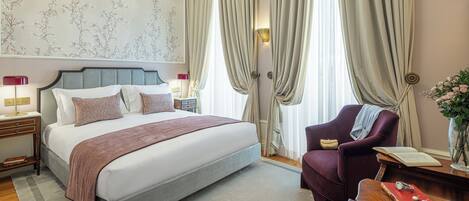 A neatly arranged bedroom with a bed, a chair, a nightstand, and a bedside table.