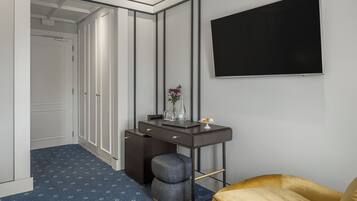 Habitación de hotel con escritorio, televisor, silla y alfombra estampada.