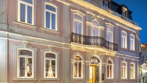 A historic building with ornate architectural details, large windows, and a balcony with a wrought iron railing.