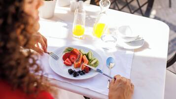 A dining table with a plate of fruit, a glass of orange juice, and a pitcher of juice.
