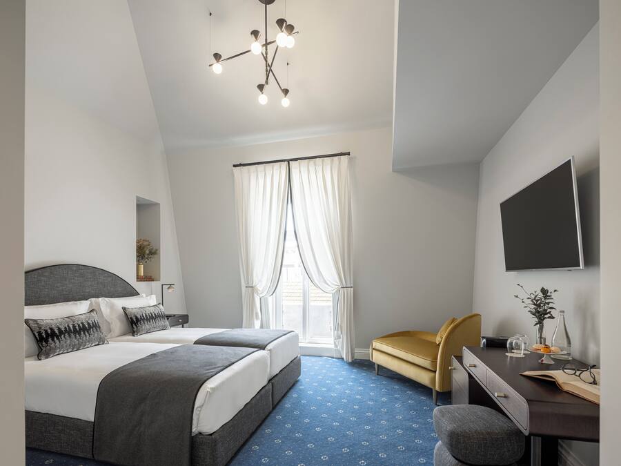 Una habitación de hotel moderna con una cama grande, un escritorio con una silla, un televisor de pantalla plana y una lámpara en el techo.