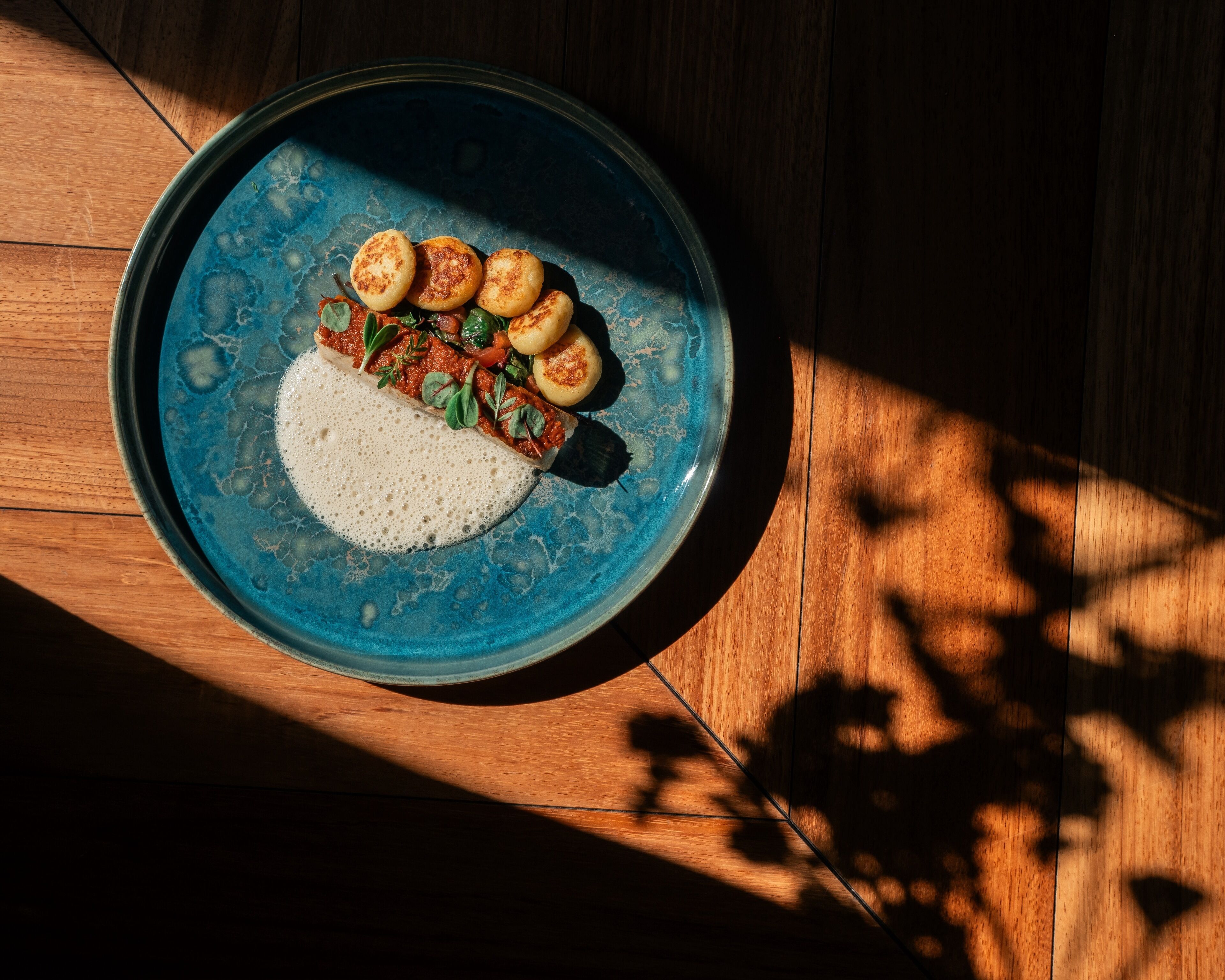 Un plato de comida sobre una fuente de cerámica azul en una mesa de madera.