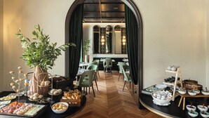 A hotel dining area with a buffet setup, including various food items and a central plant.