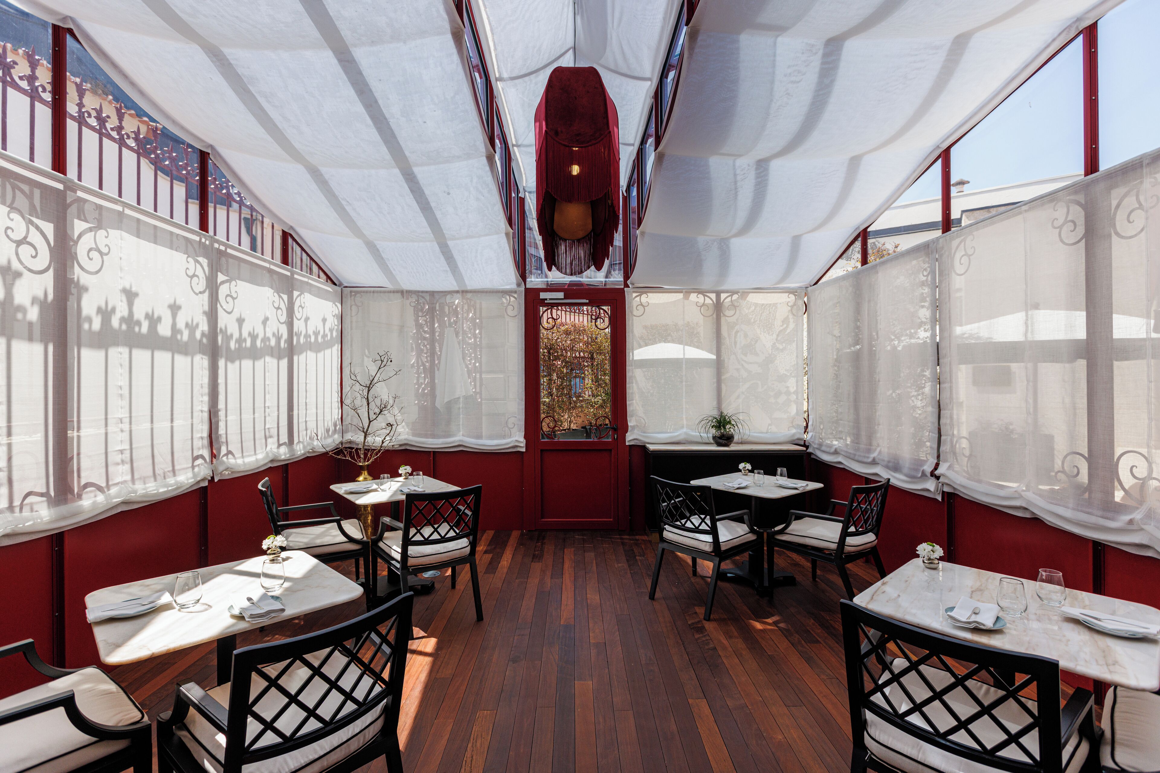 Un espace de restauration intérieur avec des tables et des chaises, un mur rouge et un plafond décoratif.