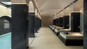 A row of spa-style massage chairs with a tiled wall and a wooden floor.