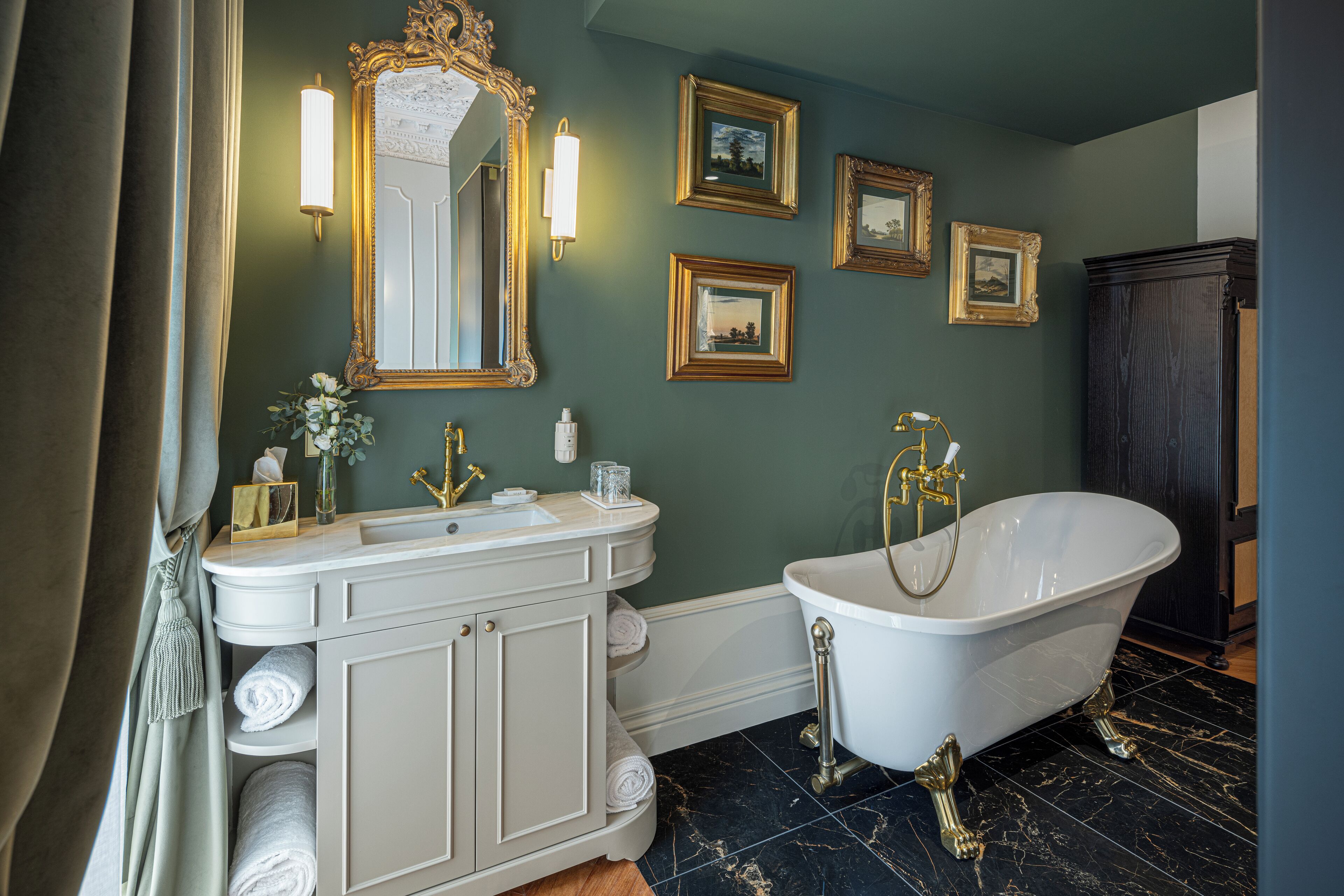 A bathroom with a white vanity, a freestanding bathtub, and framed pictures on the wall.