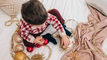A child enjoys a cozy moment on a bed with a festive atmosphere.