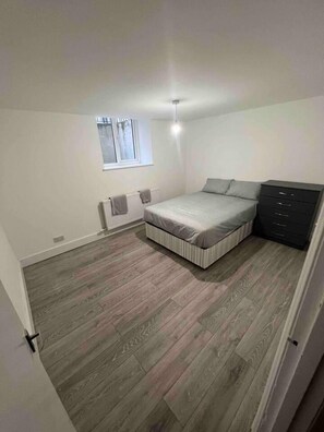 Quarto com cama, janela, radiador e cómoda.