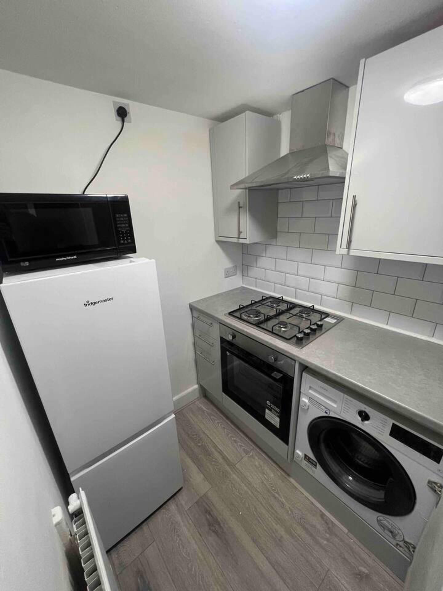 A compact kitchen with a white refrigerator, a microwave, a gas stove, an oven, and a built-in washing machine.