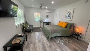A bedroom with a bed, a desk, a chair, a TV, and a window. - Studios Casa Habana (Miami)