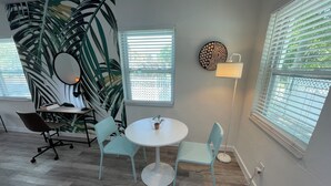 A modern room with a round table, two chairs, a desk with a chair, a large mirror, a potted plant, and a wall-mounted lamp. - Studios Casa Habana (Miami)