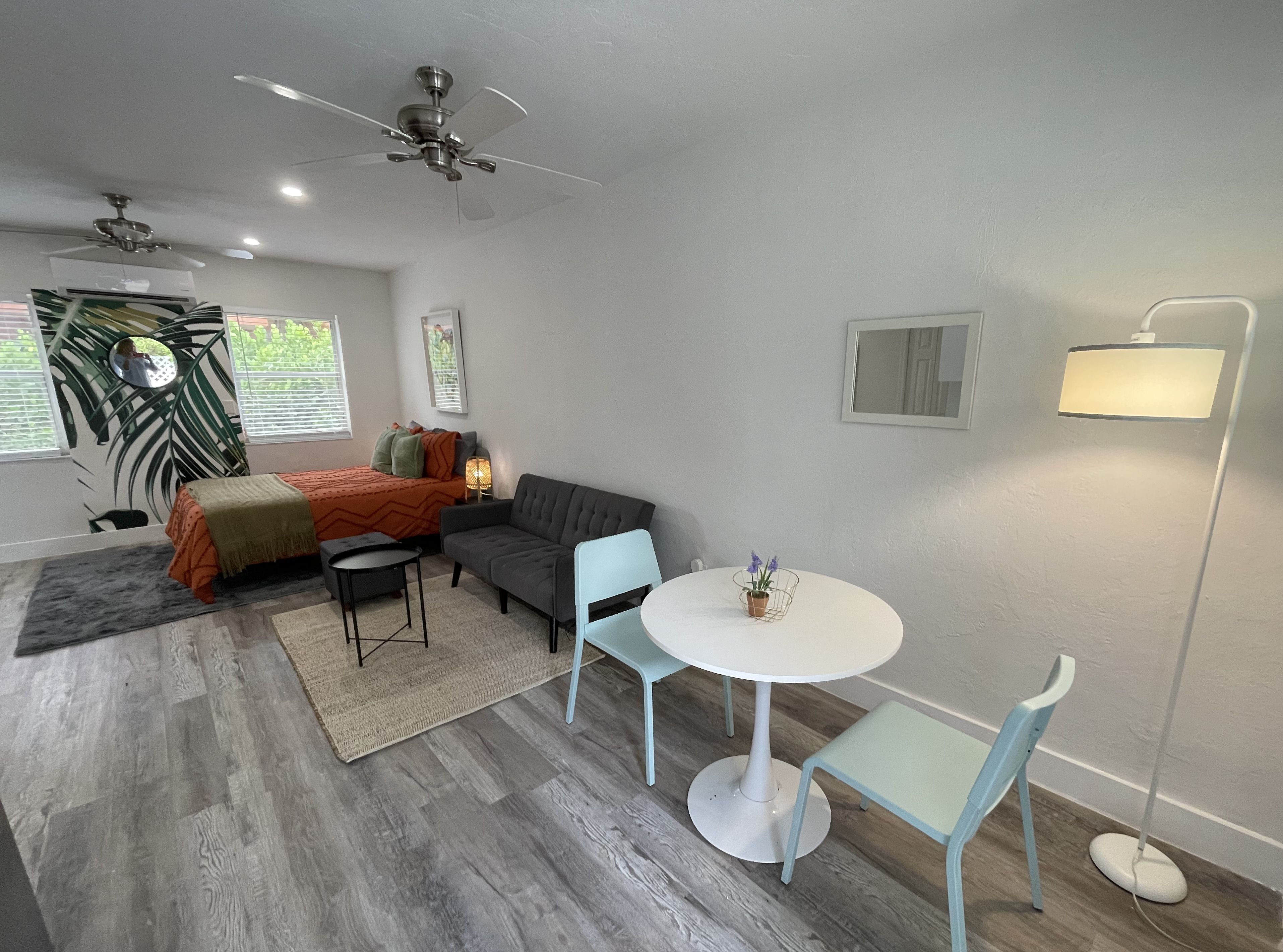 A compact room with a bed, a sofa, a small table, and a floor lamp.