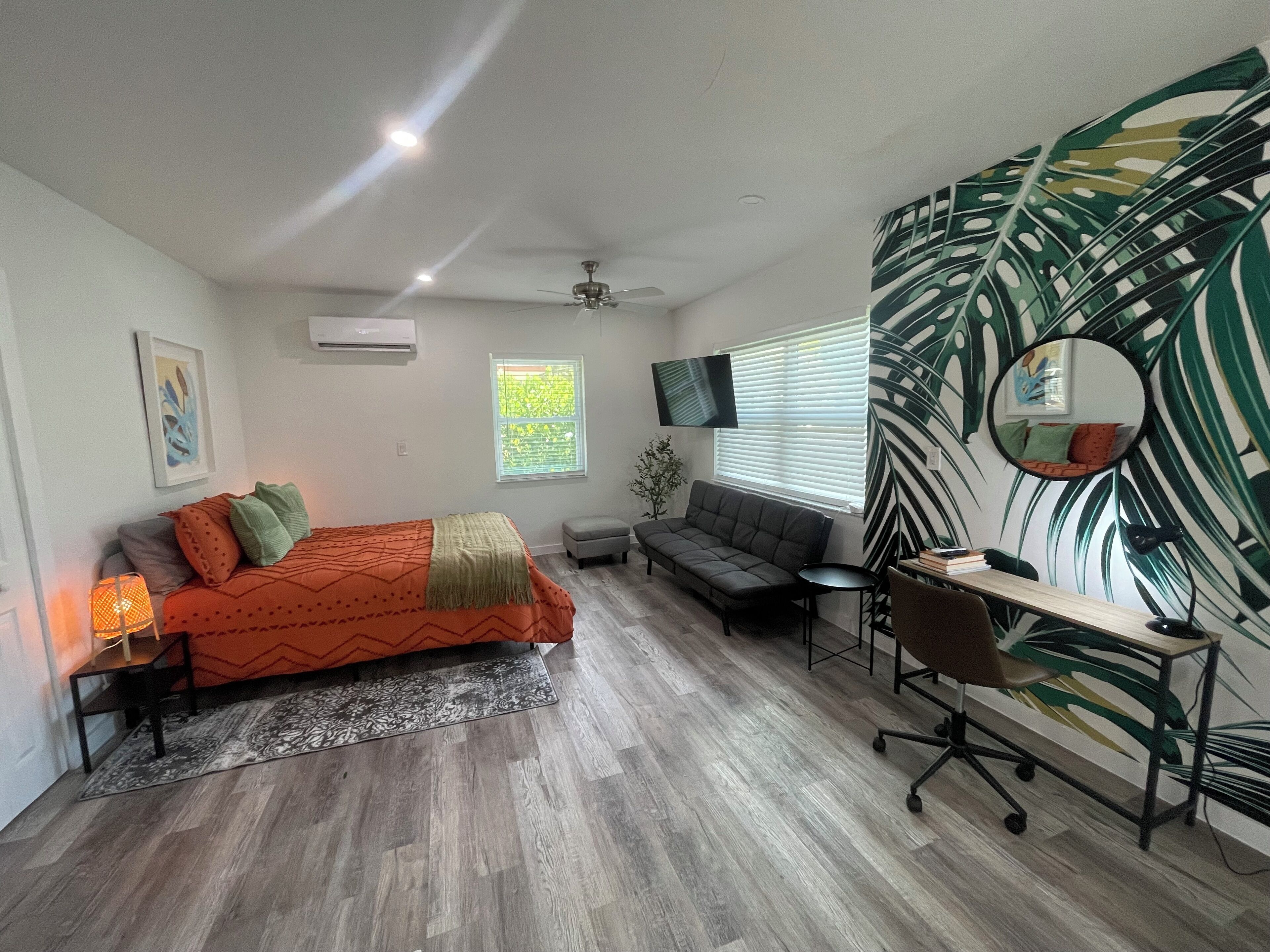 Une chambre moderne avec un lit, un bureau, un canapé et un grand miroir.