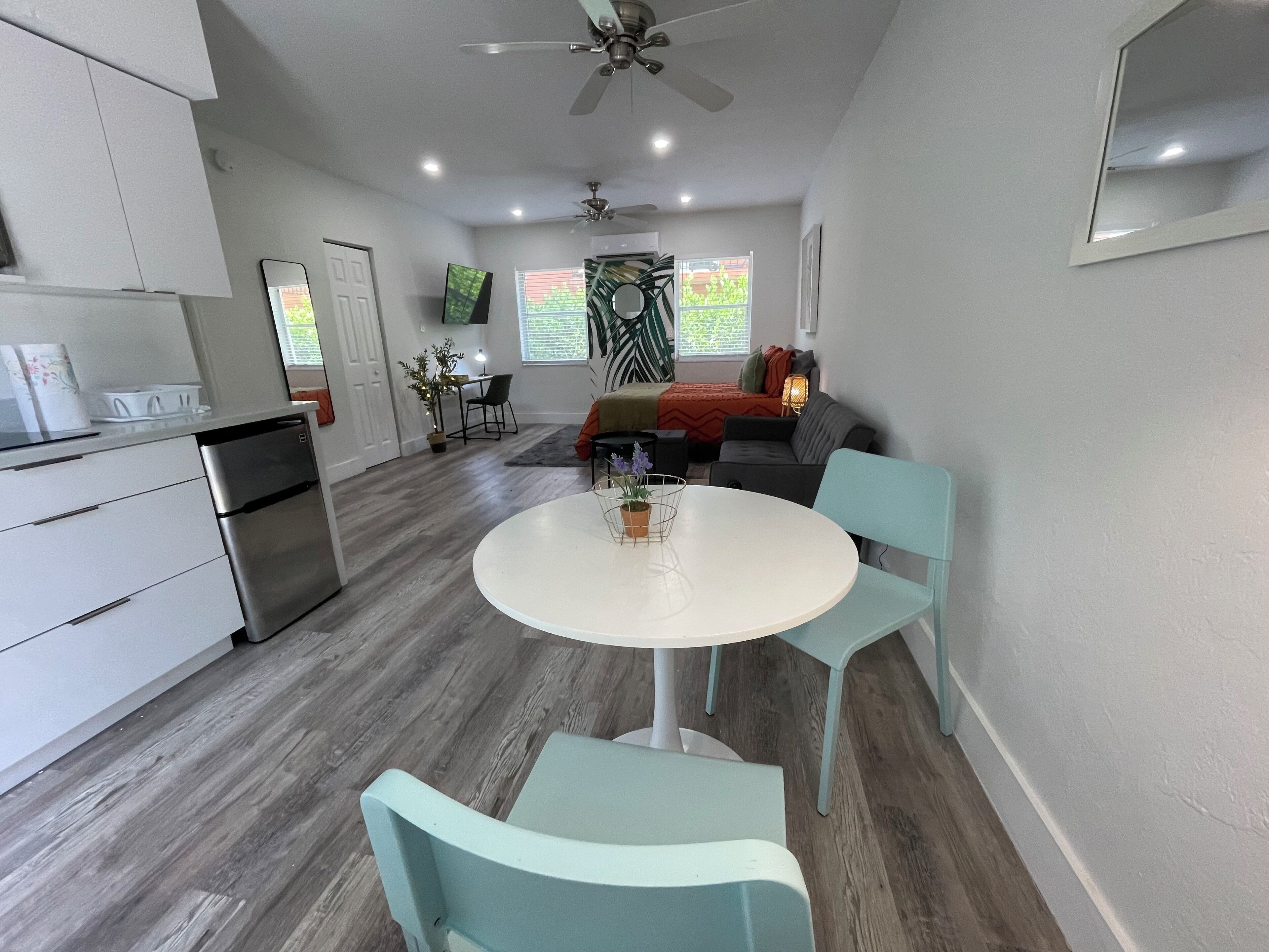 A modern kitchen with a refrigerator, stove, and dining area with a table and chairs.