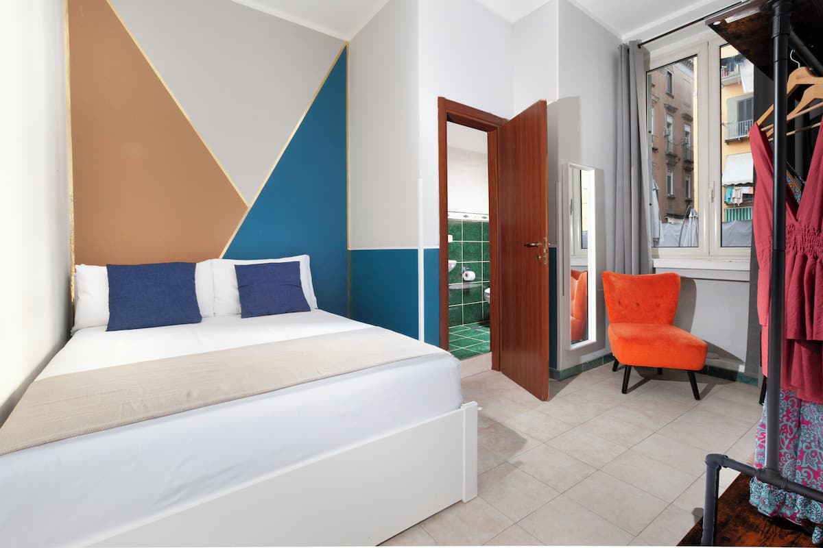 A bedroom with a bed, a chair, and a view of the outside.