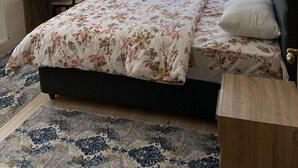 Ein Schlafzimmer mit einem Bett, einem Schreibtisch, einem Stuhl und einem großen Fenster mit Vorhängen.