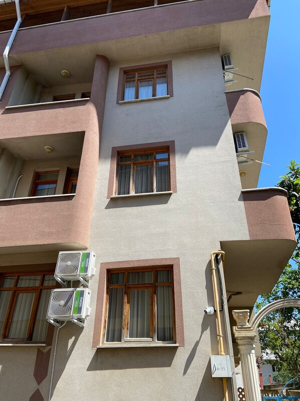 A multi-story building with several windows, air conditioning units, and a visible outdoor area with a fence. - altuncu (Trabzon)