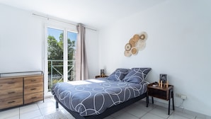 A bedroom with a bed, a dresser, a bedside table, and a wall-mounted decorative item. - La Castillane - Appt avec piscine partagée (Cavalaire-sur-Mer)