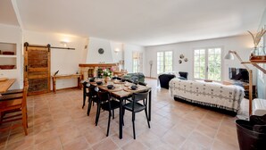 A spacious living area with a dining table set for four, a sofa, and a TV. - Casa Hestia - Avec piscine privée (Entrecasteaux)
