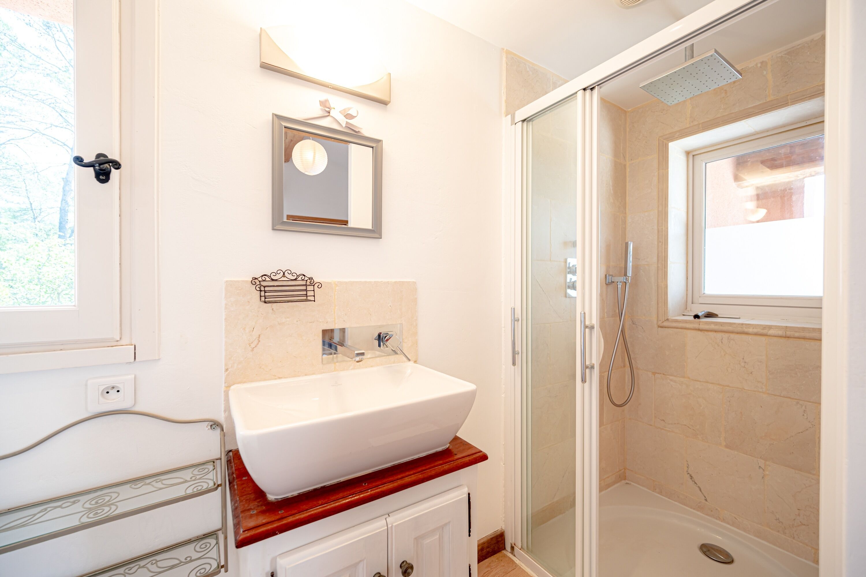 A bathroom with a white sink, a mirror, and a glass-enclosed shower.