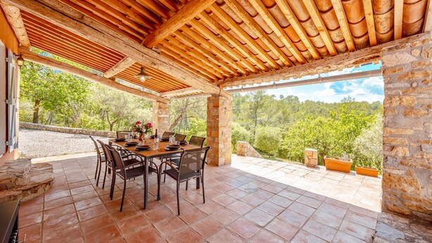 An outdoor patio with a wooden pergola, stone walls, and a dining table set for four. - Casa Hestia - Avec piscine privée (Entrecasteaux)