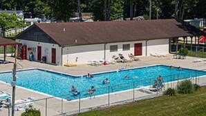 A swimming pool area with a building, a covered seating area, and trees in the background. - Near it all OC beaches,Assateague island.Family-friendly white horse park (Ocean Pines)