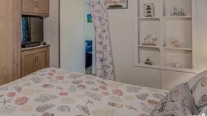 A bedroom with a bed, wooden cabinets, a ceiling fan, and a white shelf unit. - Near it all OC beaches,Assateague island.Family-friendly white horse park (Ocean Pines)