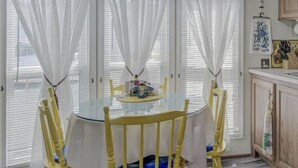 A dining area with a round table, yellow chairs, and white curtains. - Near it all OC beaches,Assateague island.Family-friendly white horse park (Ocean Pines)