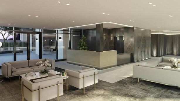 A modern lobby with a reception desk, seating area, and glass doors leading to an outdoor space.