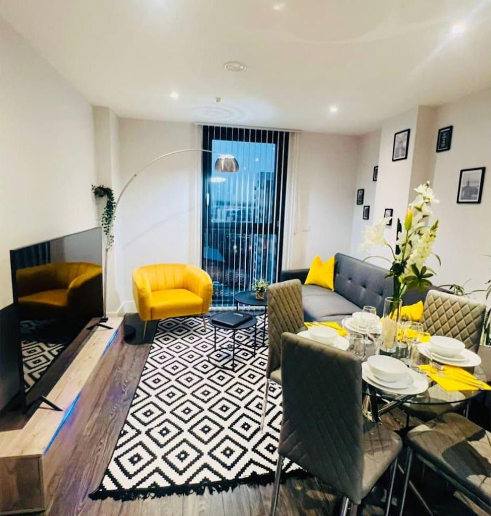 A modern living room with a sofa, yellow armchair, dining table set for four, and a patterned rug.