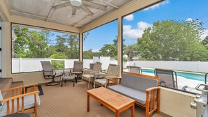 A covered outdoor area with a pool, seating, and a ceiling fan.