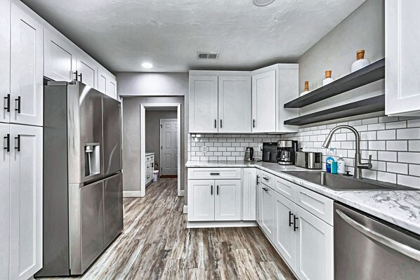 A modern kitchen with white cabinetry, stainless steel appliances, and a tiled backsplash.