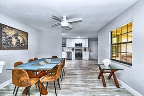 A dining area with a long table, chairs, and a ceiling fan.