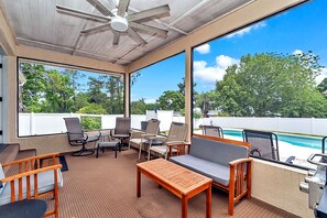 A covered outdoor area with a pool, seating, and a ceiling fan.