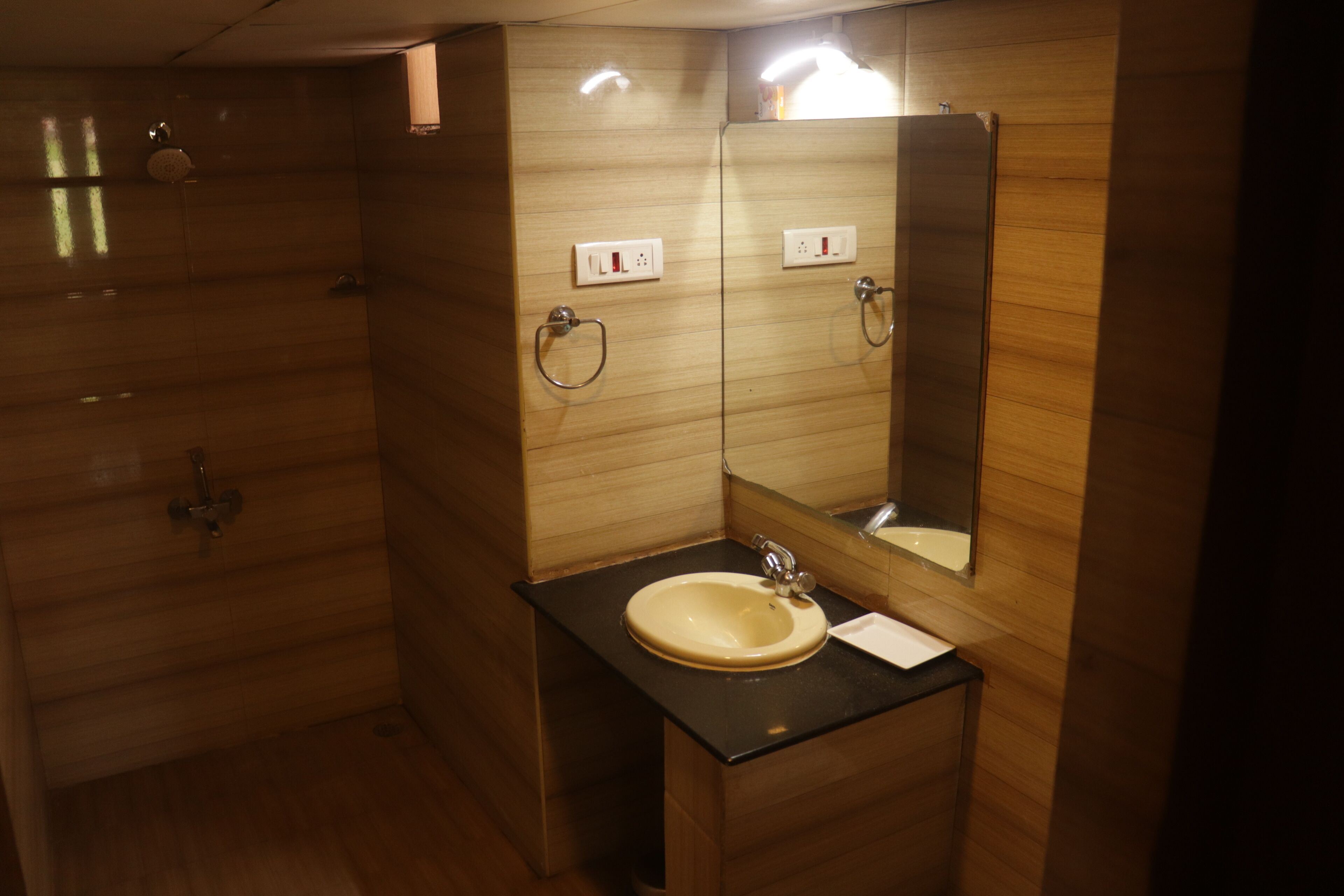A wooden bathroom with a sink, mirror, and towel rings.