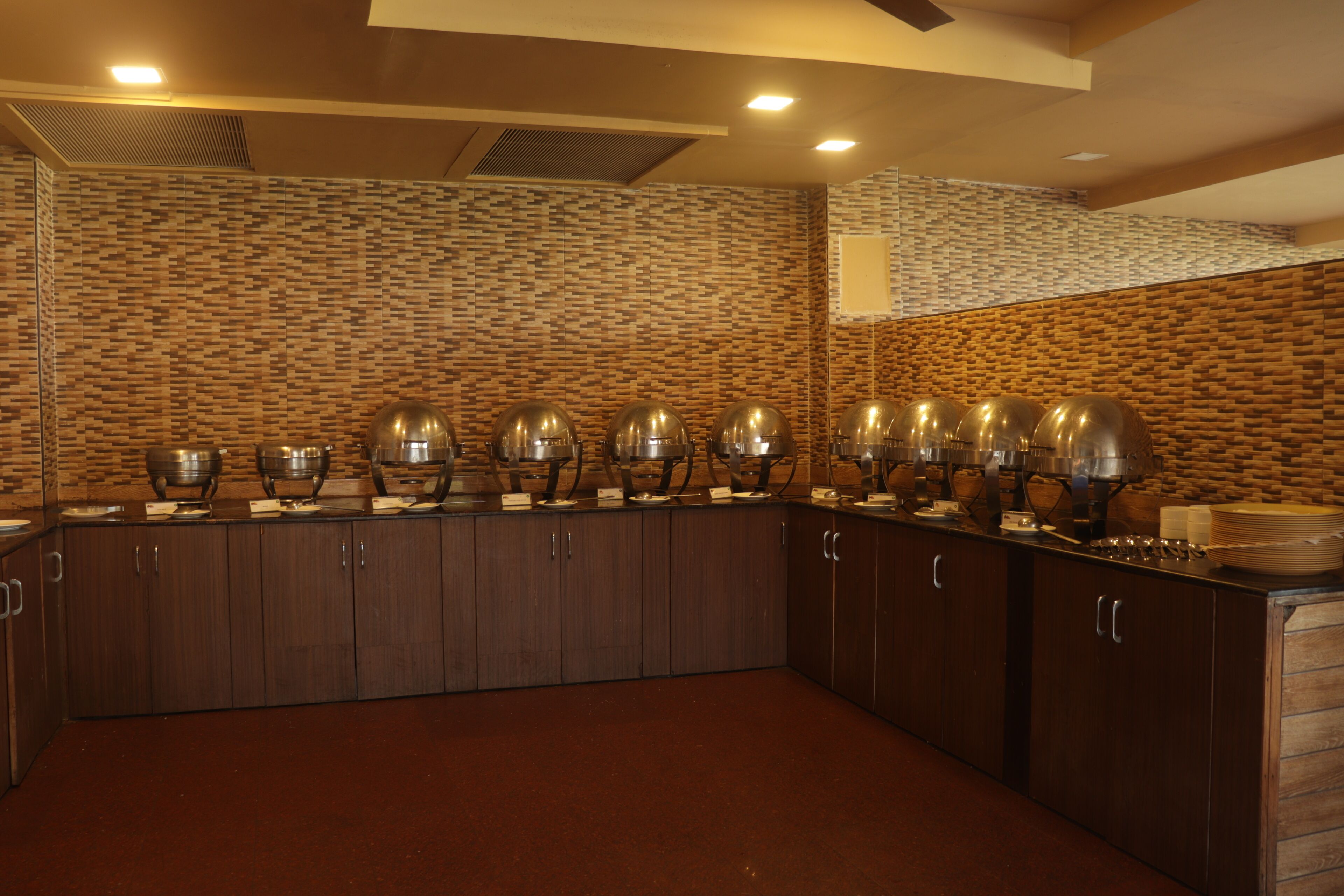 A buffet setup with multiple serving stations, a tiled backsplash, and wooden cabinetry.