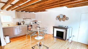 A modern kitchen with wooden beams, a dining area with a glass table, and a fireplace.