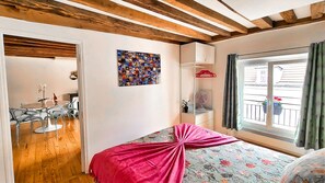 Un dormitorio con una cama, una ventana con cortinas, techo de madera y una pared con un collage de fotos.