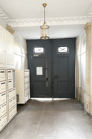 Un pasillo con una puerta gris oscuro, una lámpara y varios archivadores beige.