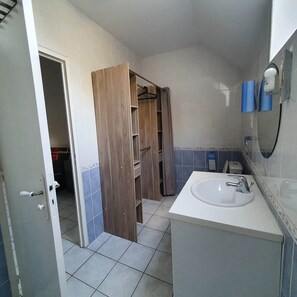 Ein Badezimmer mit einem weißen Waschbecken, einem Holzschrank und einer blauen Fliesenwand.