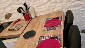 A wooden dining table set with red plates, cutlery, and a glass. - Studio "nid Cosy" Avec Piscine Chauffée (Bonnemain)