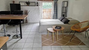 A small, well-lit room with a bed, a desk, a chair, and a television. - Studio "nid Cosy" Avec Piscine Chauffée (Bonnemain)