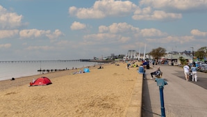 Une plage avec des tentes, des gens et une jetée en arrière-plan.