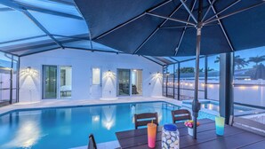 Un espace aménagé au bord de la piscine, avec une table, des chaises et un grand parasol.