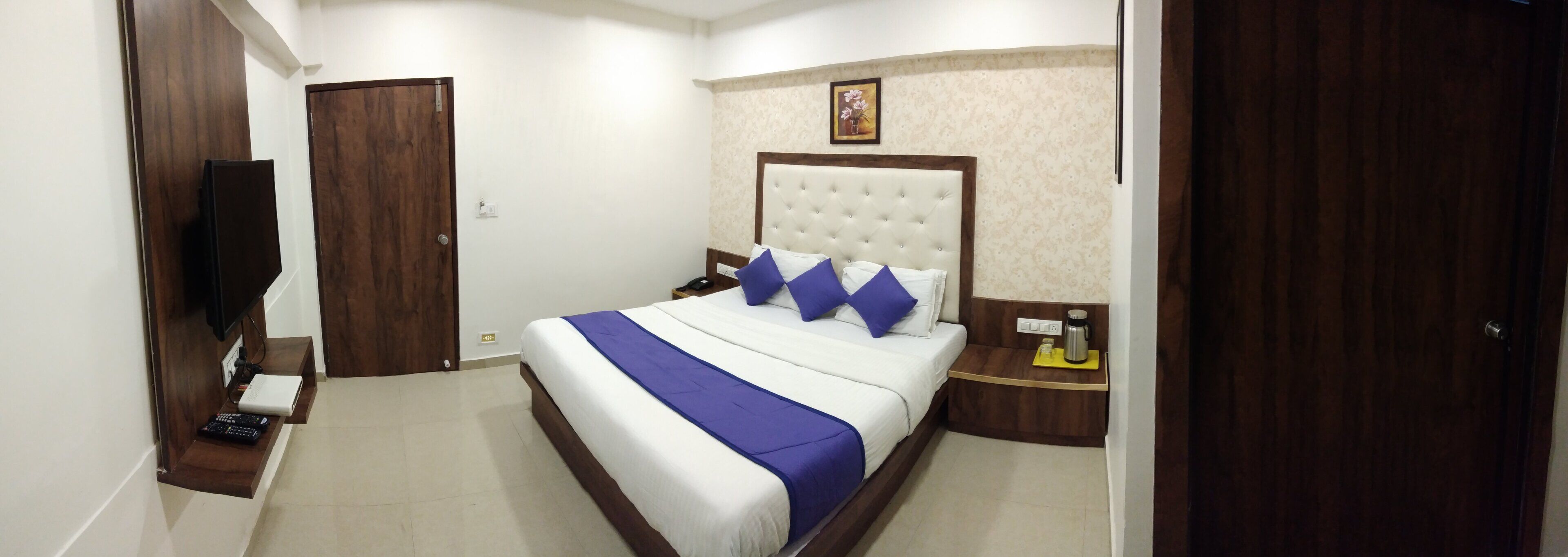 Una habitación de hotel con cama, mesita de noche y televisor.